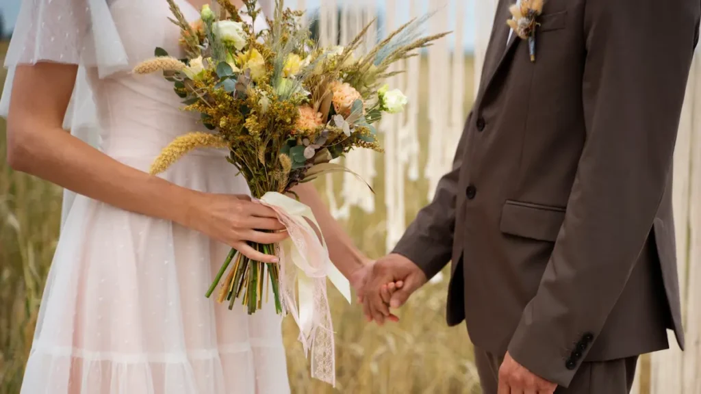 Novios en bodas en Montilla tomados de la mano con ramo de flores silvestres en entorno rústico