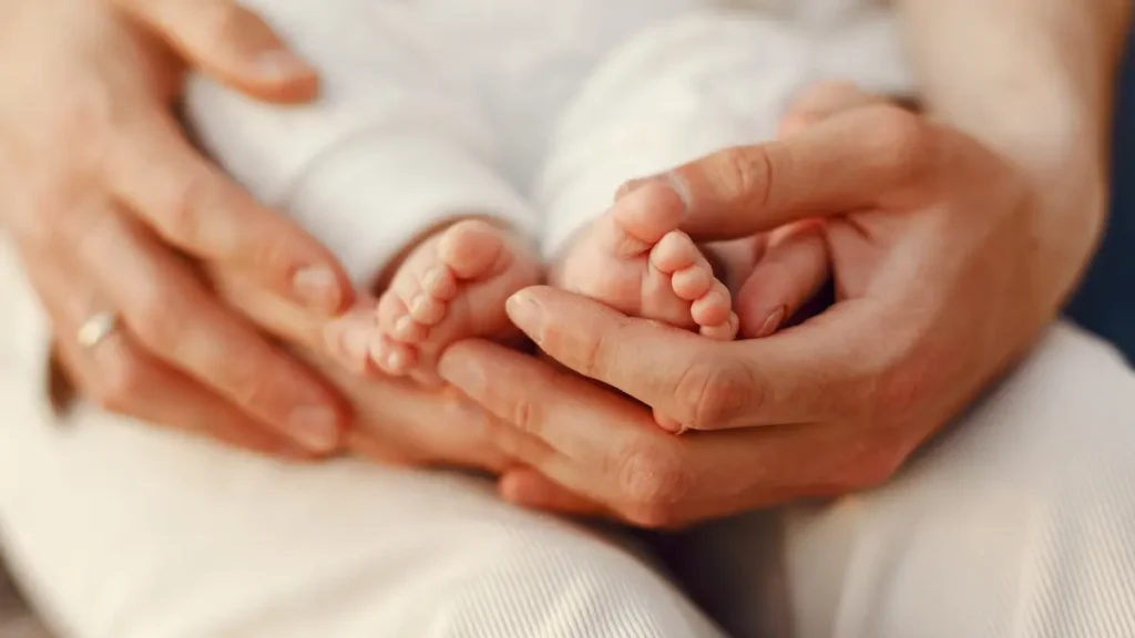 Detalle de los pequeños pies de un recién nacido entre las manos de sus padres en una sesión de fotos newborn en Córdoba y Montilla