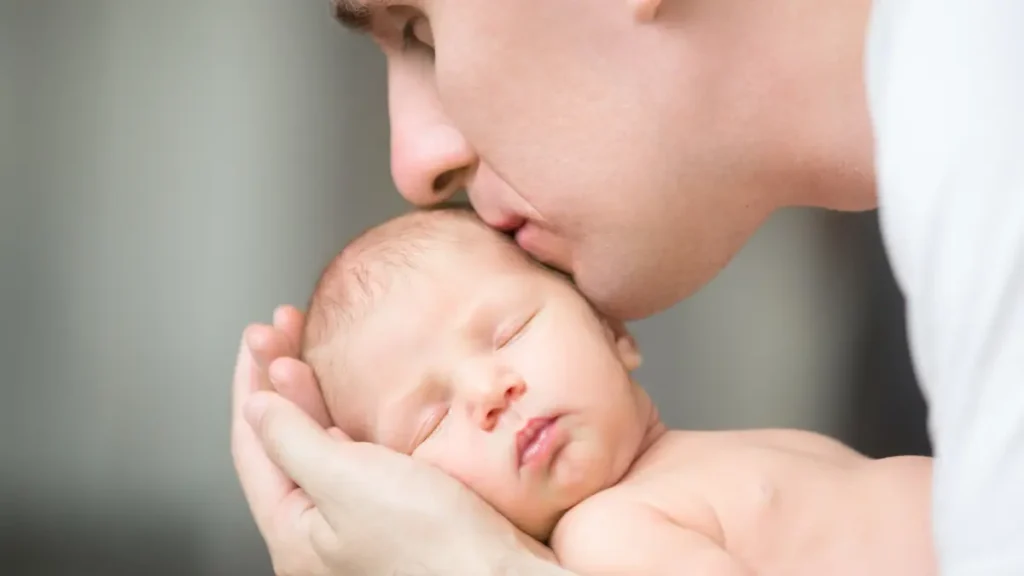 Padre besando tiernamente la cabeza de su recién nacido durante una sesión de fotos newborn en Córdoba y Montilla