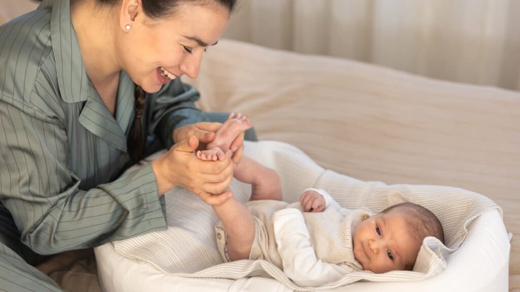Madre sonriendo mientras juega con los pies de su bebé recién nacido en una sesión de fotos newborn en Córdoba y Montilla